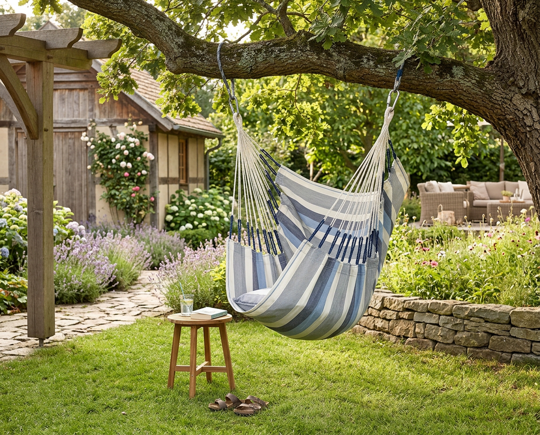 Blue and cream LA SIESTA Cumbia Outdoor Sea Salt hammock chair hanging from a tree in a garden