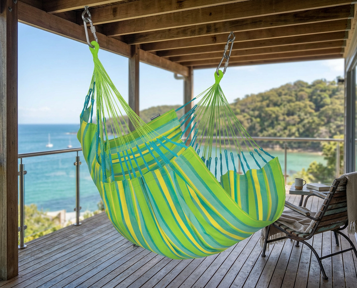 Green LA SIESTA Cumbia Outdoor Lime hammock chair hanging on a covered deck overlooking the sea