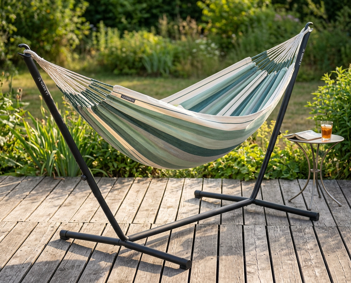 Green and cream LA SIESTA Modesta Olive hammock on a black Nautico stand on a garden deck