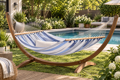Blue and white striped LA SIESTA Alisio Sea Salt hammock on a wooden arc stand by a pool (stand sold separately)