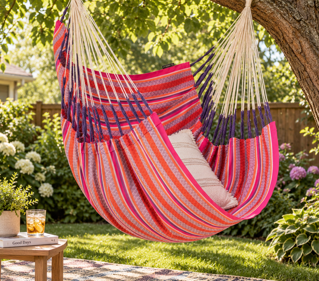 Pink LA SIESTA Cumbia Organic Flamingo hammock chair hanging from a tree in a garden